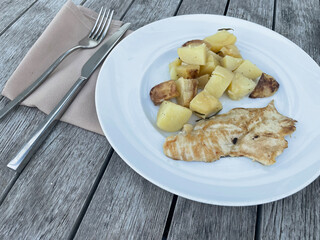 Appetizing grilled chicken fillet served with roasted potatoes on a white ceramic plate