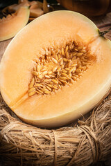 A juicy halved cantaloupe sits on a wooden table, still life,close-up
