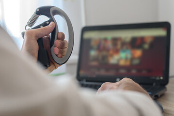 Strength training with hand expander while watching online content