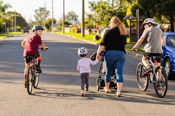 Family on walk down street in Australian country town boys on bike and mum holding toddlers hand