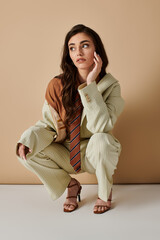 Fashionable young woman in stylish suit poses creatively in studio setting