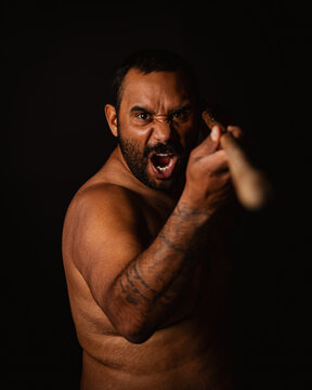 Aboriginal man pointing spear to camera yelling