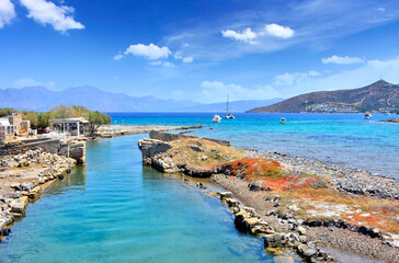 Elounda canal and peaceful Mediterranean sea with turquoise water, rocky hills in the background, Crete, Greece