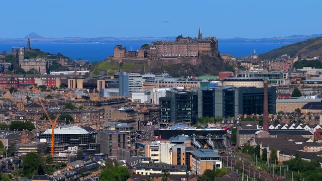 Aerial video of Edinburgh from the west side with zoomed view of the Castle on the Rock, cityscape, sea in the background