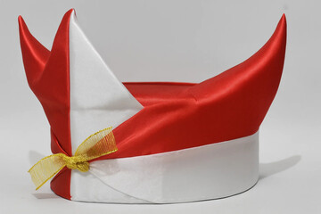 Traditional headpiece, red and white horn-shaped Indonesian headband with golden ribbon, symbolizing heritage, national identity, and cultural celebration.

