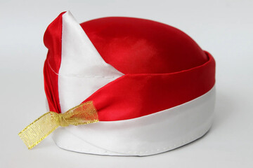 Traditional headgear, round red and white Indonesian cap with golden ribbon, symbolizing national pride, cultural identity, and independence celebration.

