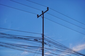 Chaotic utility pole silhouettes against the sky, photographed from below in the midday