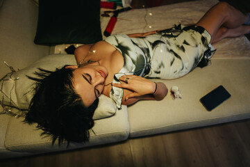 A fashionable woman is lounging on a couch during a home celebration, exuding relaxation and style....