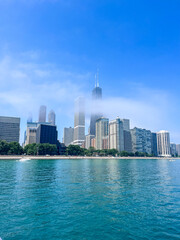 Obraz premium Beautiful sunny day in Chicago, Illinois. Views of the skyline above the bright blue sky and water in Lake Michigan.