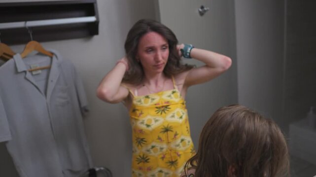 Mother and daughter getting ready in the bathroom, styling hair together near the mirror.
