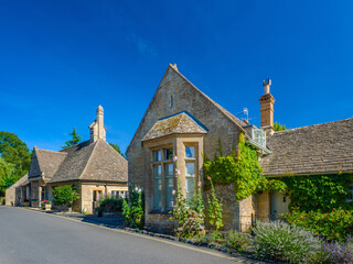 Traditional Cotswold cottage with a bay window, ivy, and blooming garden (Lower Slaughter, Gloucestershire, England, United Kingdom)
