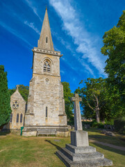 Looking up at The Parish Church of Saint Mary's spire and churchyard cross (Lower Slaughter, Gloucestershire, England, United Kingdom)