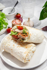 Appetizing Shawarma with chicken and fresh vegetables on a light background