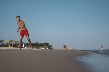 Summer Energy: Teen Boy Playing on the Beach. Teen Boy’s Summer Vacation by the Sea

