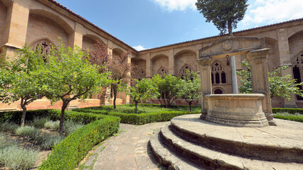Catedral de Siguenza in Spain features serene courtyard with fountain and lush greenery, offering a...