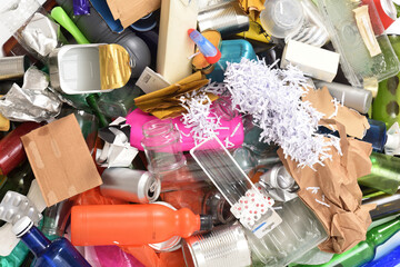 close up of garbage with plastic containers, glass, cans, paper and medicine on white background