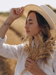 Young woman resting and relaxing with closed eyes holding bunch of ripe wheat ears in her hand