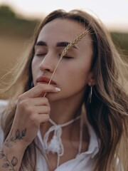 Young woman with wheat spikelet in her hand resting and relaxing with closed eyes on wheat field.