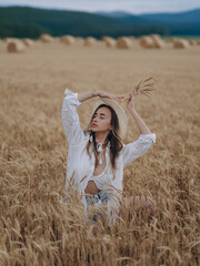 Young woman resting and relaxing with closed eyes holding bunch of ripe wheat ears in her hand.