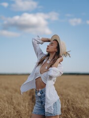 Young woman resting and relaxing with closed eyes holding bunch of ripe wheat ears in her hand.