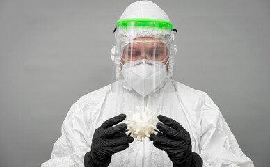 Nurse in protective gear handling a coronavirus model in a clinical environment during the COVID-19...
