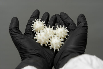 Hands holding models of coronavirus demonstrating the impact of covid on health and society