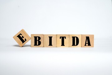 EBITDA writing on a wooden block. Bright white background.