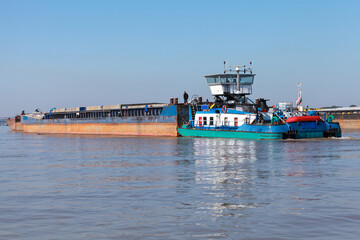 Rear view of a blue and white tugboat pushing a barge on Danube river,