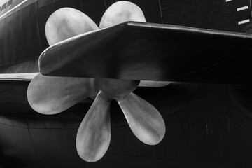 Black and white photography featuring massive submarine boat propeller