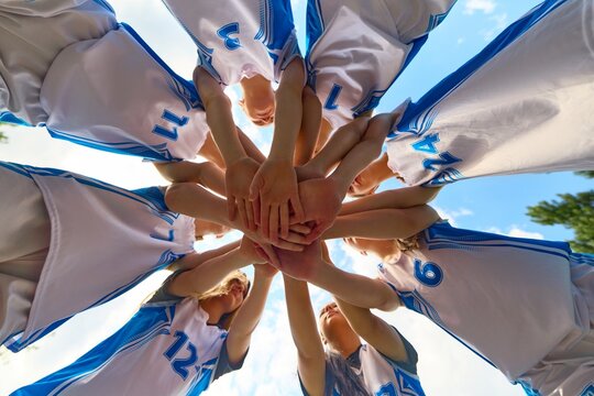 Women basketball team gathering in a motivational huddle in uniform outside. Concept of unity and symmetry, basketball motivation visuals, empowering youth energy, promotional sports identity
