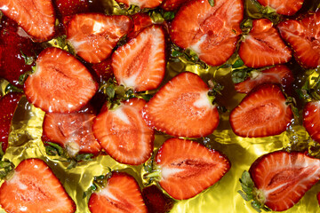 Halves of fresh ripe strawberries in water, summer juicy fruit berry background.