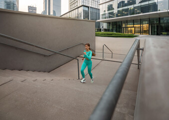 Fit woman in turquoise activewear is exercising outdoors, climbing stairs with determination, showcasing strength and fitness lifestyle. Workout concept