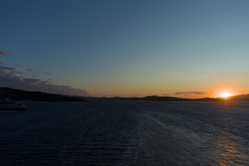 The setting sun creates a vibrant orange glow on the horizon, casting a soft light over the calm...