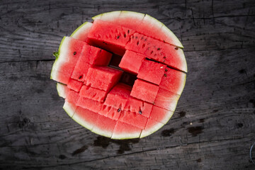 A top-down view of a refreshing watermelon, partially cut into juicy cubes, resting on a rustic...