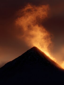 A mountain peak bathed in the golden light of a dramatic sunset.