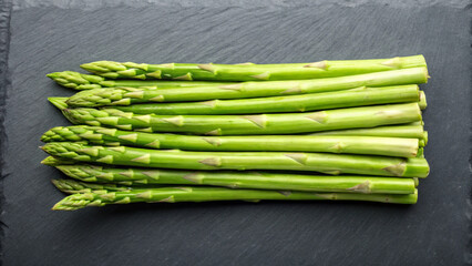Fresh green asparagus spears arranged neatly on a dark textured surface ready for cooking