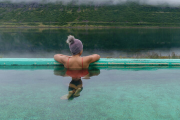 Relaxing in a geothermal hot spring with stunning Icelandic landscape views during a cloudy day