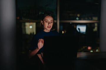 A dedicated businesswoman works intently on her laptop at night, focusing in a dimly lit office setting. The image captures the essence of dedication and productivity during late hours.