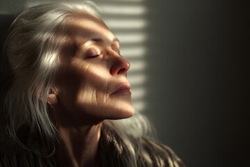 An older white woman with silver hair, eyes closed in serenity, sunlight streaking across her face from half-drawn blinds deep focus,