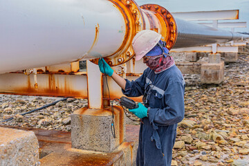 Male worker inspection and measurement thickness of rusted steel pipe, steel deterioration,...