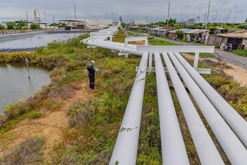 Male worker inspection at steel long pipes and pipe elbows inthe  station oil factory during refinery valve of visual check record pipeline tank oi