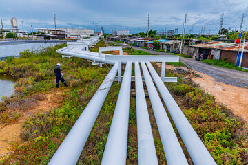 Naklejka premium Male worker inspection at steel long pipes and pipe elbows inthe station oil factory during refinery valve of visual check record pipeline tank oi