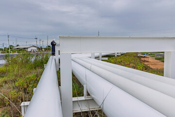 Male worker inspection at steel long pipes and pipe elbows inthe  station oil factory during refinery valve of visual check record pipeline tank oi