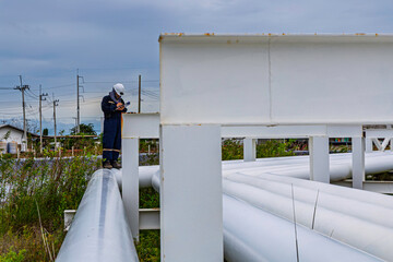 Male worker inspection at steel long pipes and pipe elbows inthe  station oil factory during refinery valve of visual check record pipeline tank oi