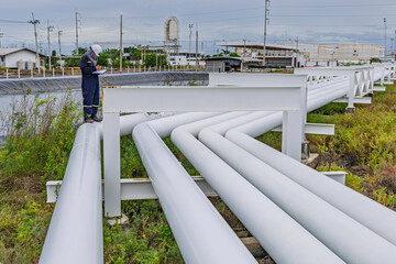 Male worker inspection at steel long pipes and pipe elbows inthe  station oil factory during...