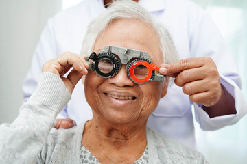 Optometrist checking Asian elderly woman ophthalmic vision eye test and using optical trial frame.