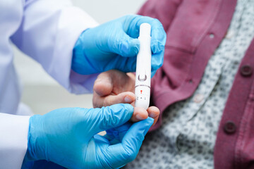 Asian senior woman using lancet pen on senior patient finger for check sample blood sugar level to treatment diabetes.