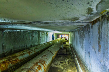 Male worker inspection of rusted steel pipe, underground steel deterioration, widespread corrosion,...
