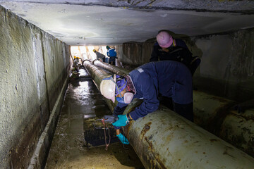 Male worker inspection of rusted steel pipe, underground steel deterioration, widespread corrosion,...
