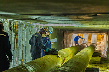 Male worker inspection of rusted steel pipe, underground steel deterioration, widespread corrosion, and confined spaces